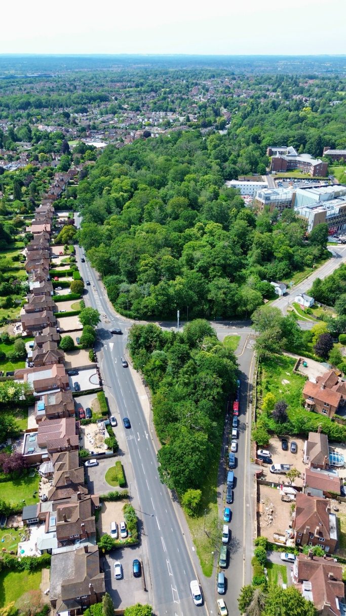 Aerial view of a suburban area with trees, roads, and residential buildings.