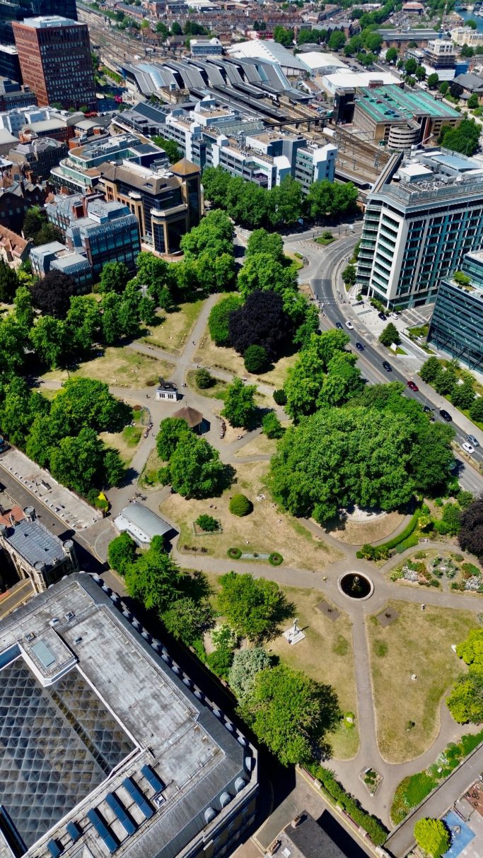 Aerial view of a green park surrounded by urban buildings and roads.