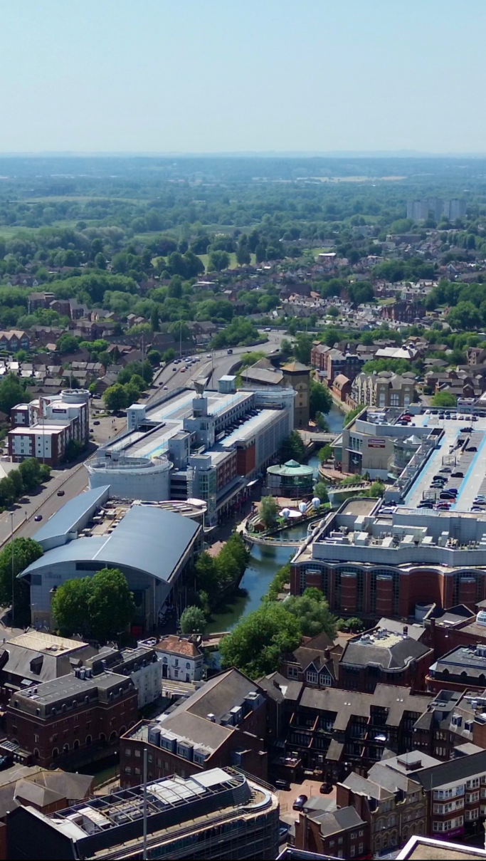 Aerial view of a town with buildings, greenery, and waterways.