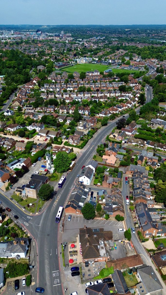 Aerial view of suburban area with a road, houses, and green spaces.