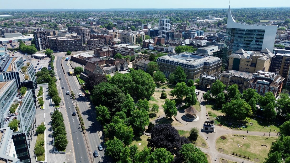 Aerial view of a cityscape with greenery and roads, showcasing urban development.